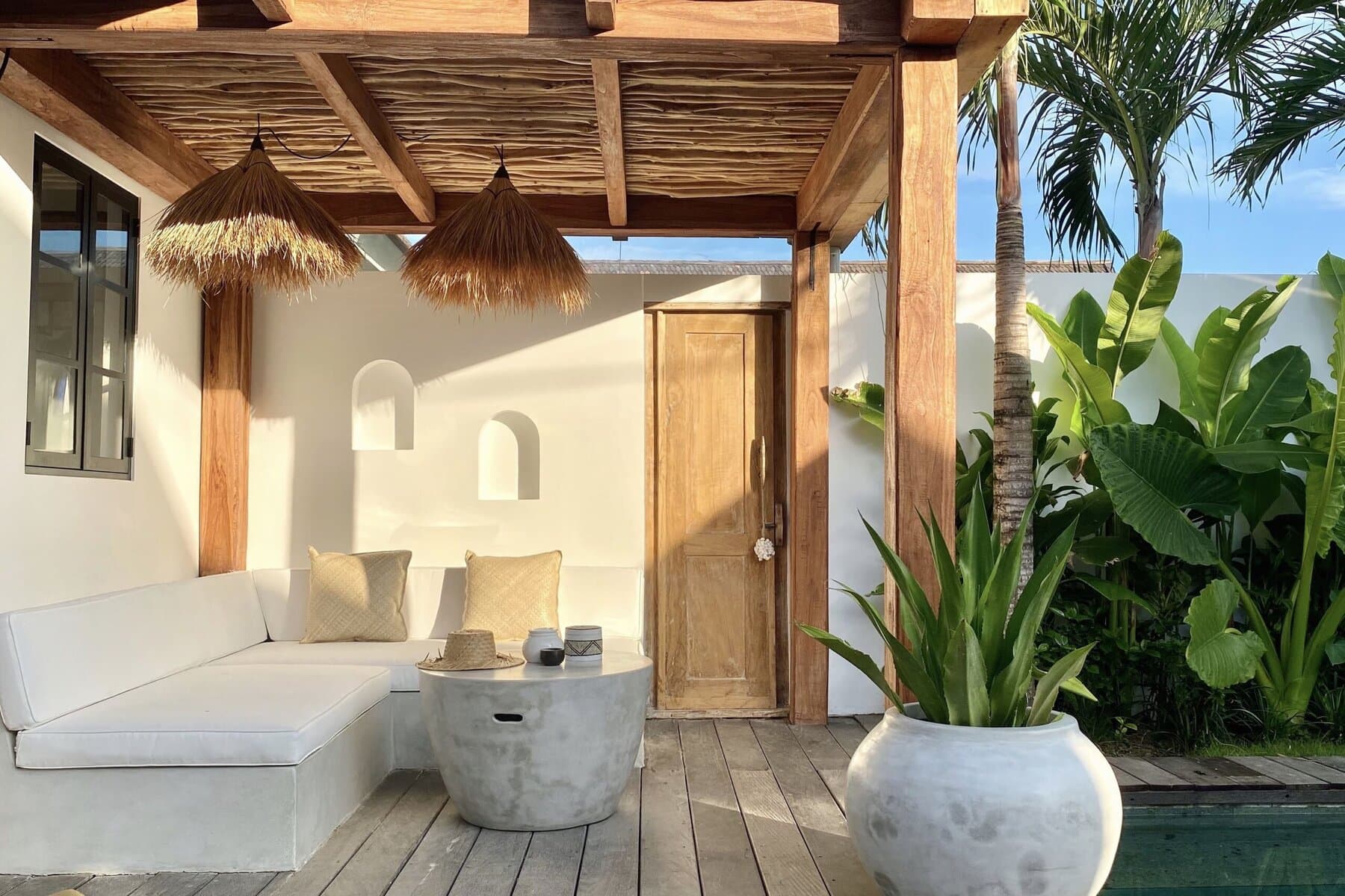 Elegant outdoor lounge area featuring white seating and lush greenery.