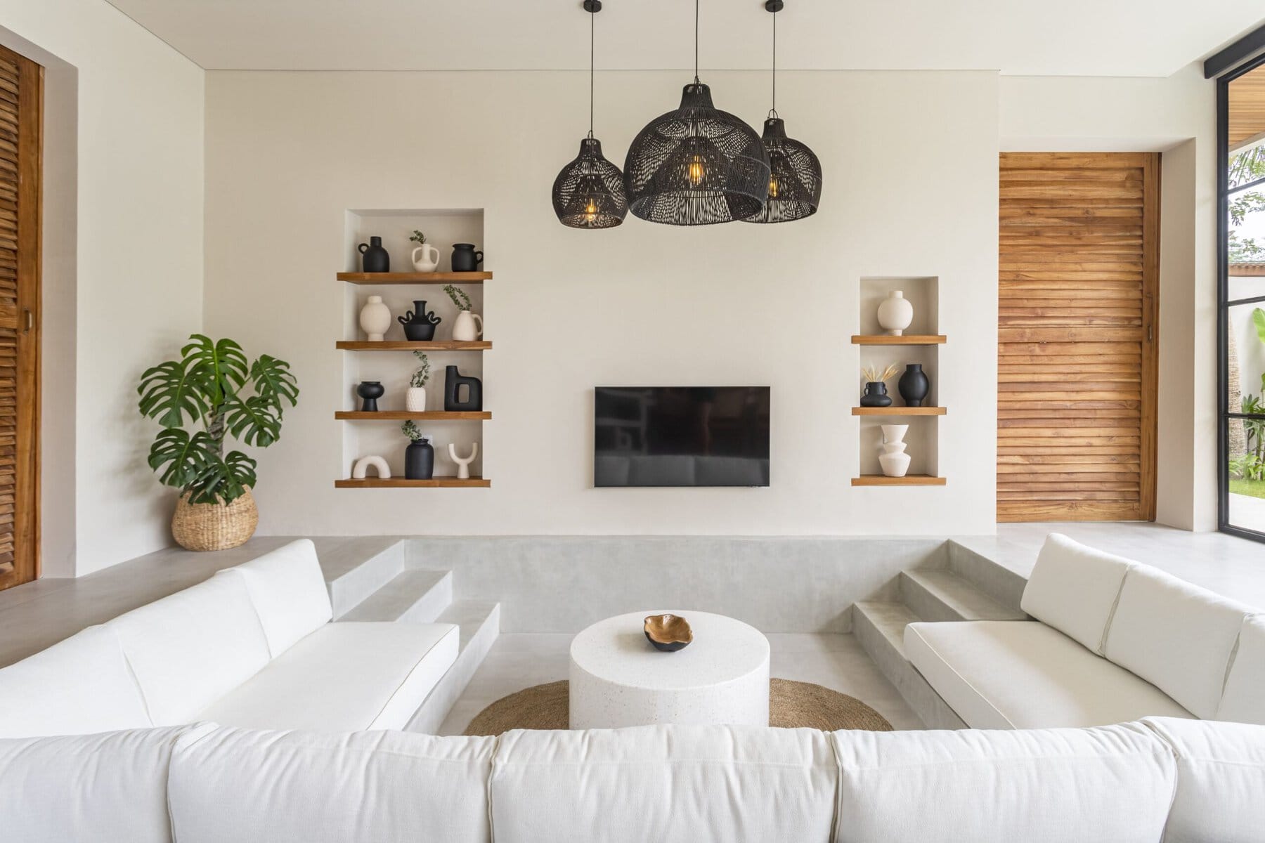 Bright, modern living room with white sofas, black pendant lights, and decorative shelves.