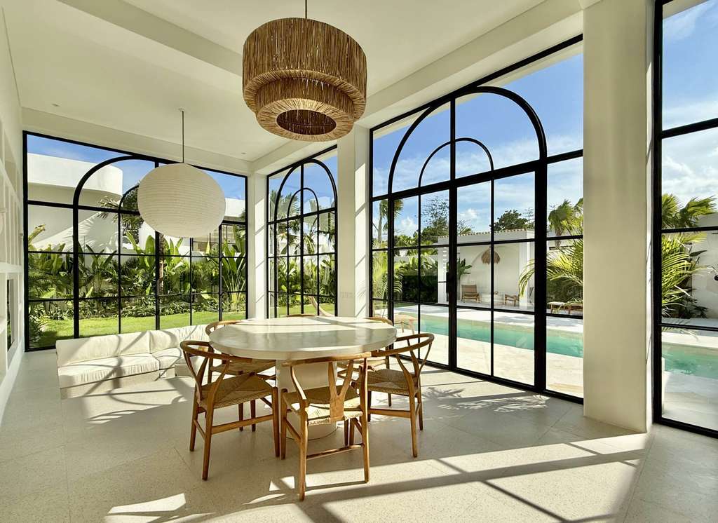 Luxurious Bali villa interior with large glass windows, pool access, and tropical garden views in Uluwatu.