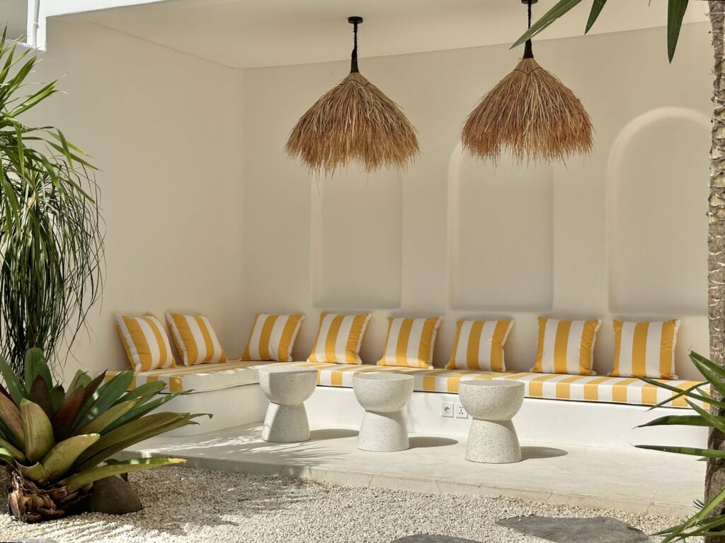 High-end villa outdoor lounge with tropical decor, striking striped cushions, and natural pendant lighting in Uluwatu.