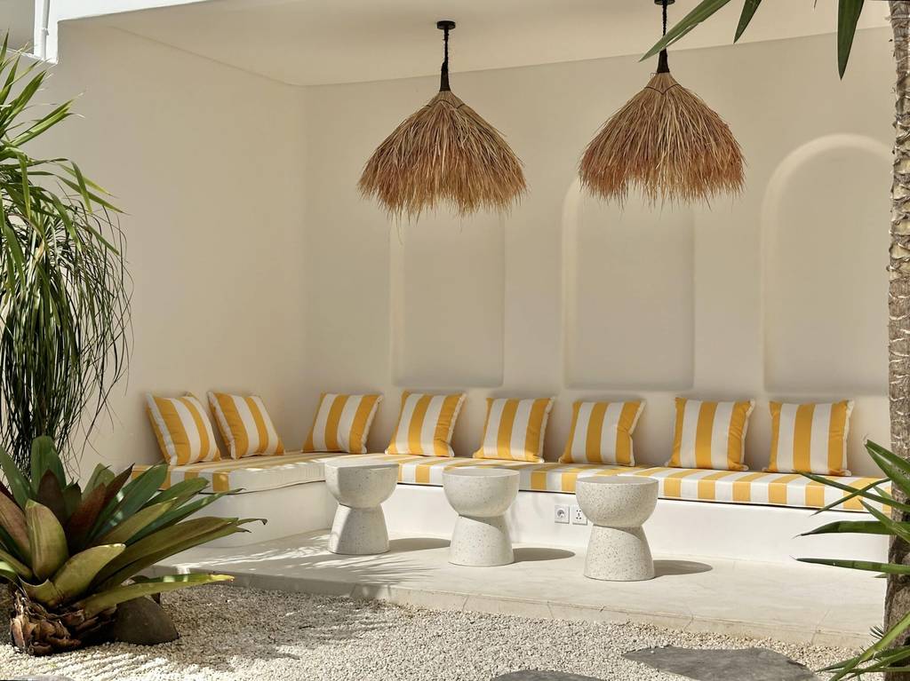 High-end villa outdoor lounge with tropical decor, striking striped cushions, and natural pendant lighting in Uluwatu.