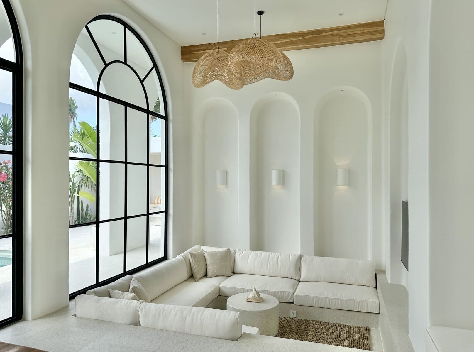 Modern luxury Bali villa living room with high ceilings and large arched windows.