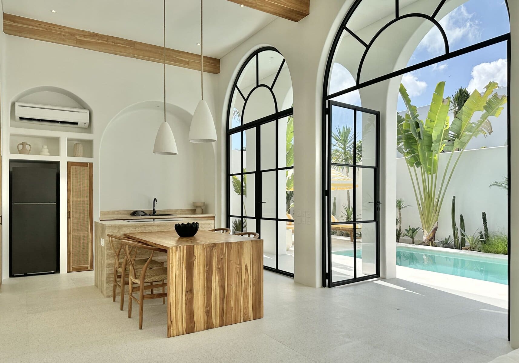 Bright, open-plan living space with large arched windows and pool view.
