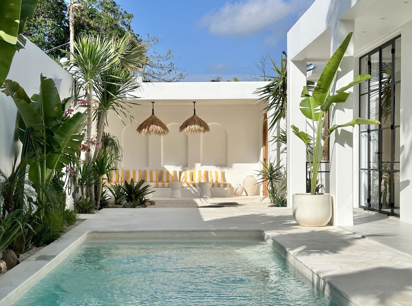 Stunning white villa with pool, lush green plants, and modern tropical design in Uluwatu.