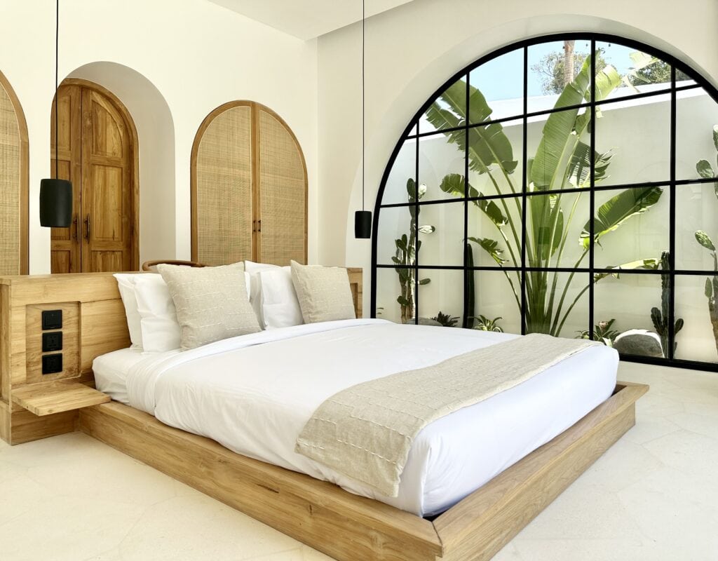 Stylish bedroom with wooden accents, large window views of lush greenery, and modern comforts.
