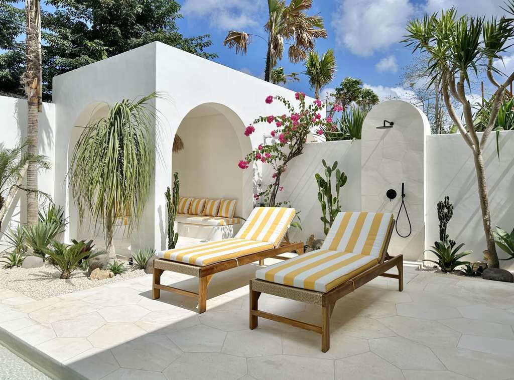 Outdoor Bali villa with pristine white walls, lush greenery, and stylish lounging area.