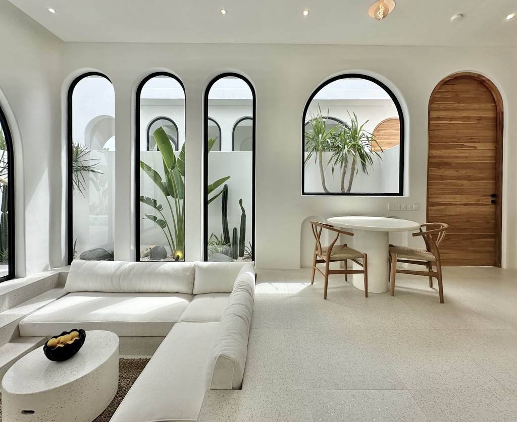 Modern minimalistic Bali villa living space with natural light and lush indoor plants.
