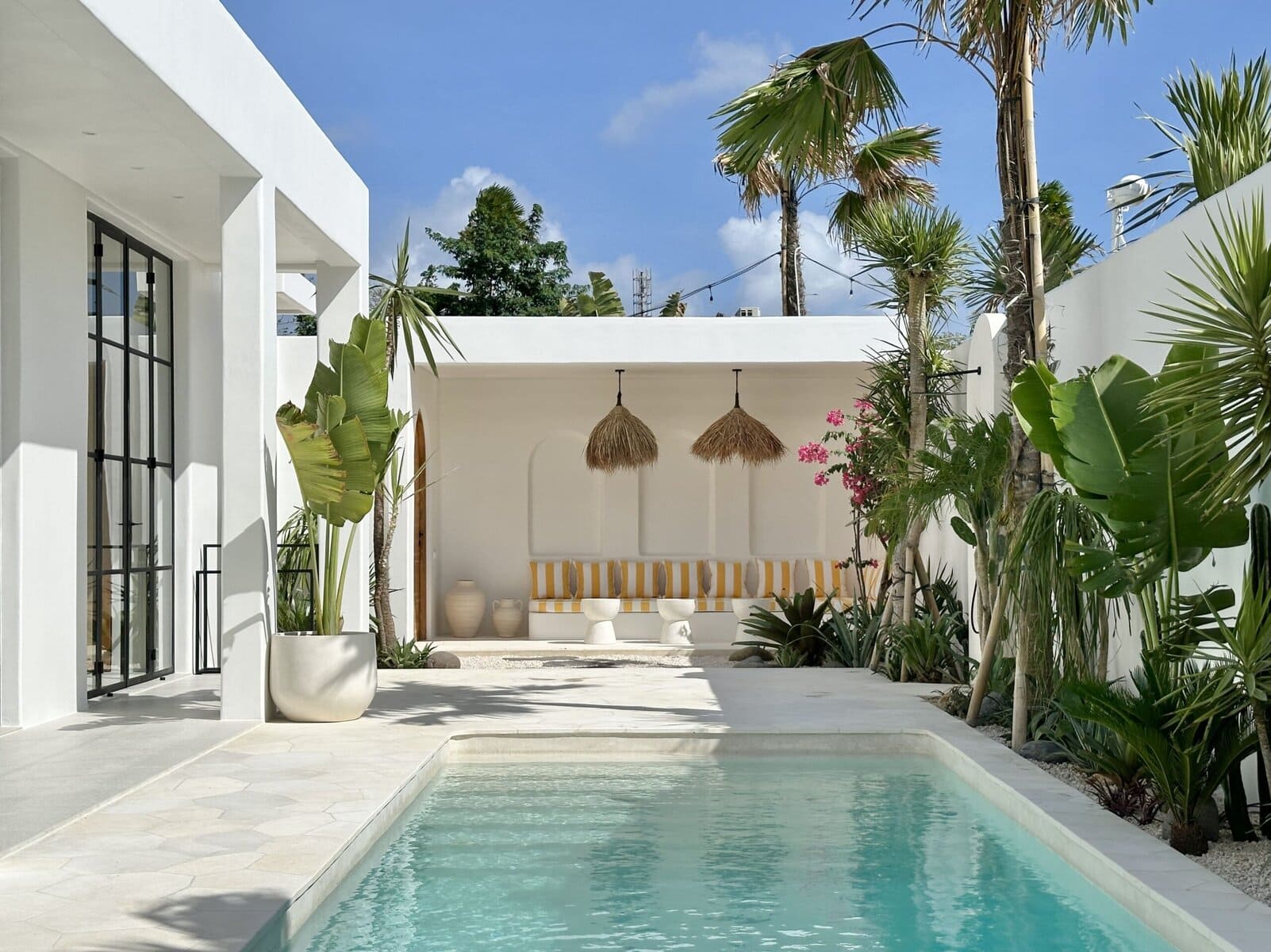 White contemporary villa with pool, lush greenery, and Bali tropical-modern style, ideal for a luxury Uluwatu getaway.