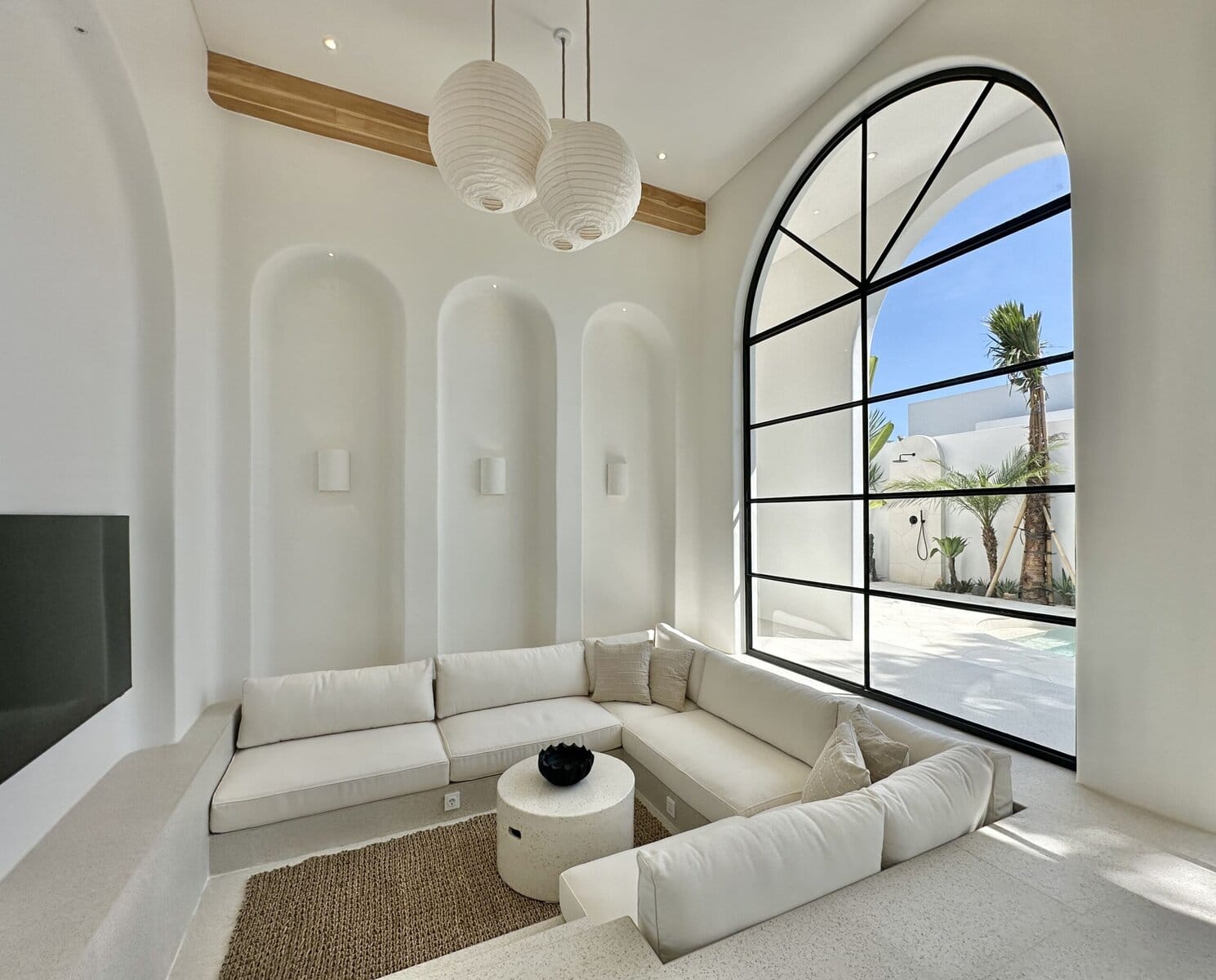 Bright modern lounge with large arched window and tropical views.
