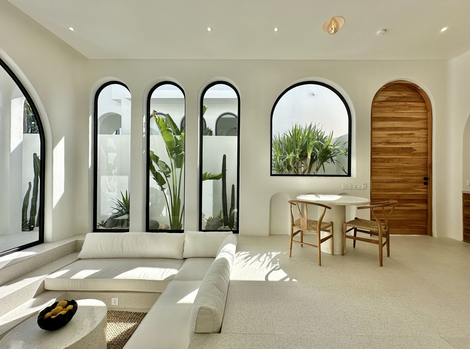 Modern Bali villa interior with arched windows, lush greenery, and elegant wooden accents.