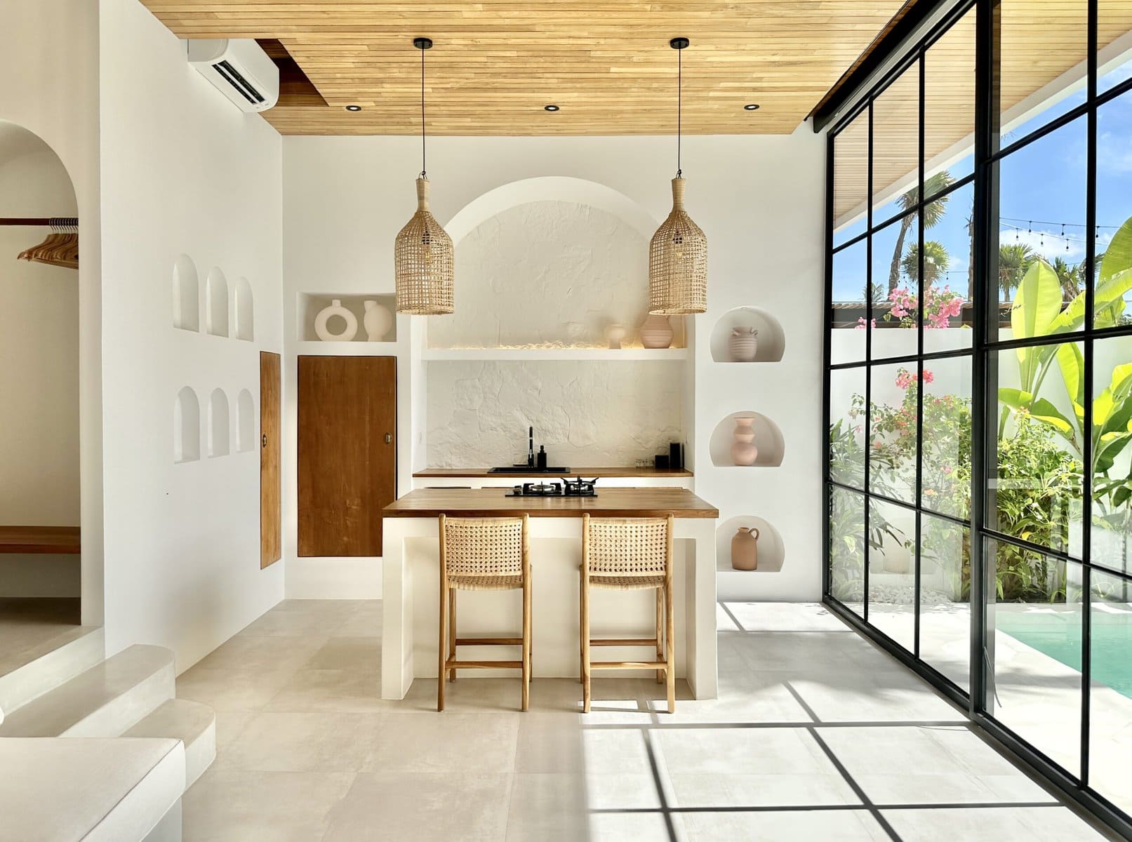 Bright, modern Bali villa with minimalist decor, wood accents, and expansive glass walls bringing nature inside.