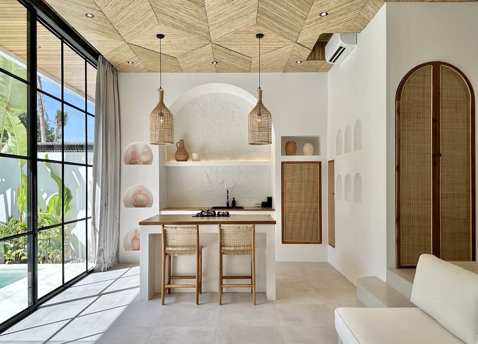 Bright Bali villa interior with white walls, wood accents, and scenic outdoor views.