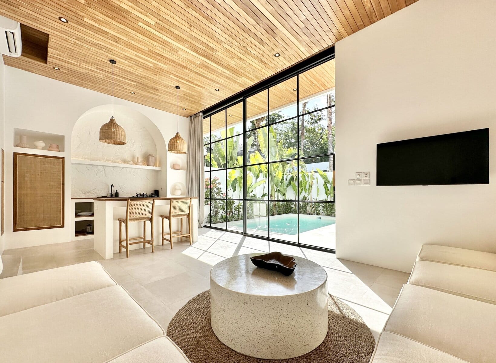 Sunny bali villa living room featuring white walls, wood accents, and access to outdoor pool area.