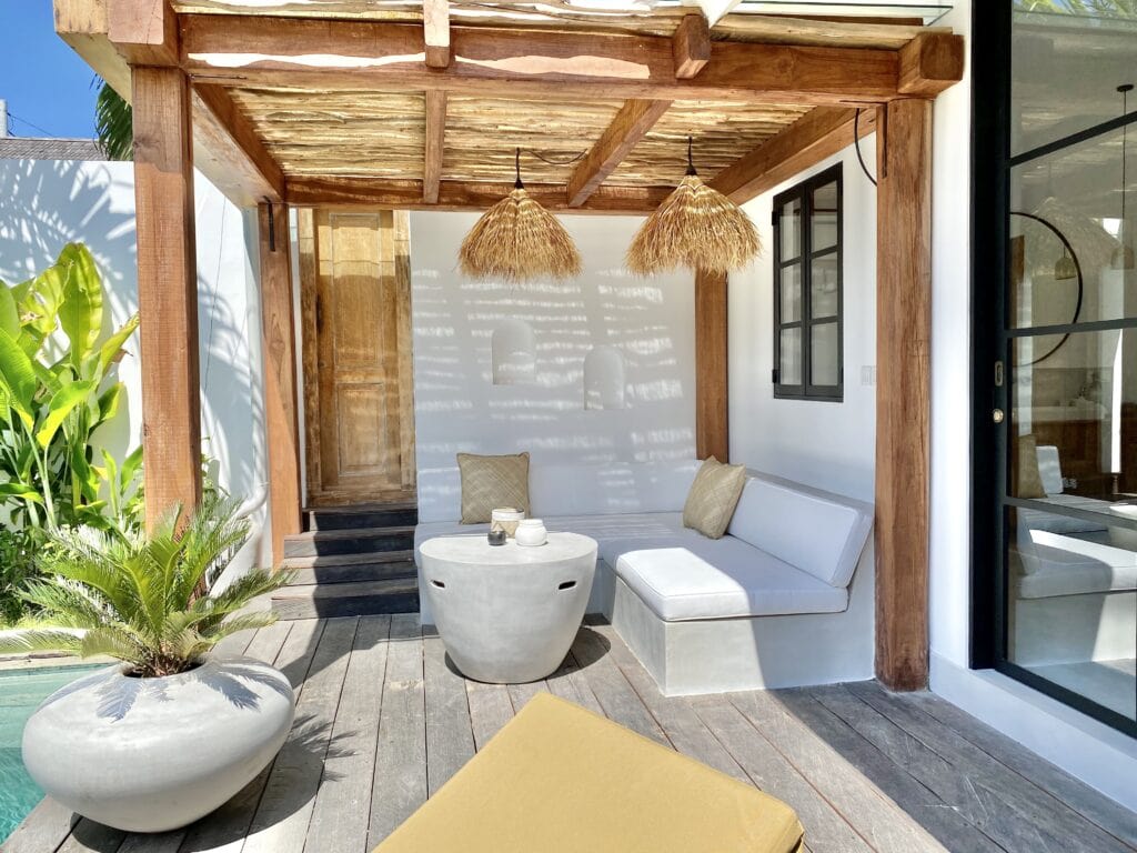 Spacious outdoor terrace with white seating, wooden accents, and lush greenery in Bali.
