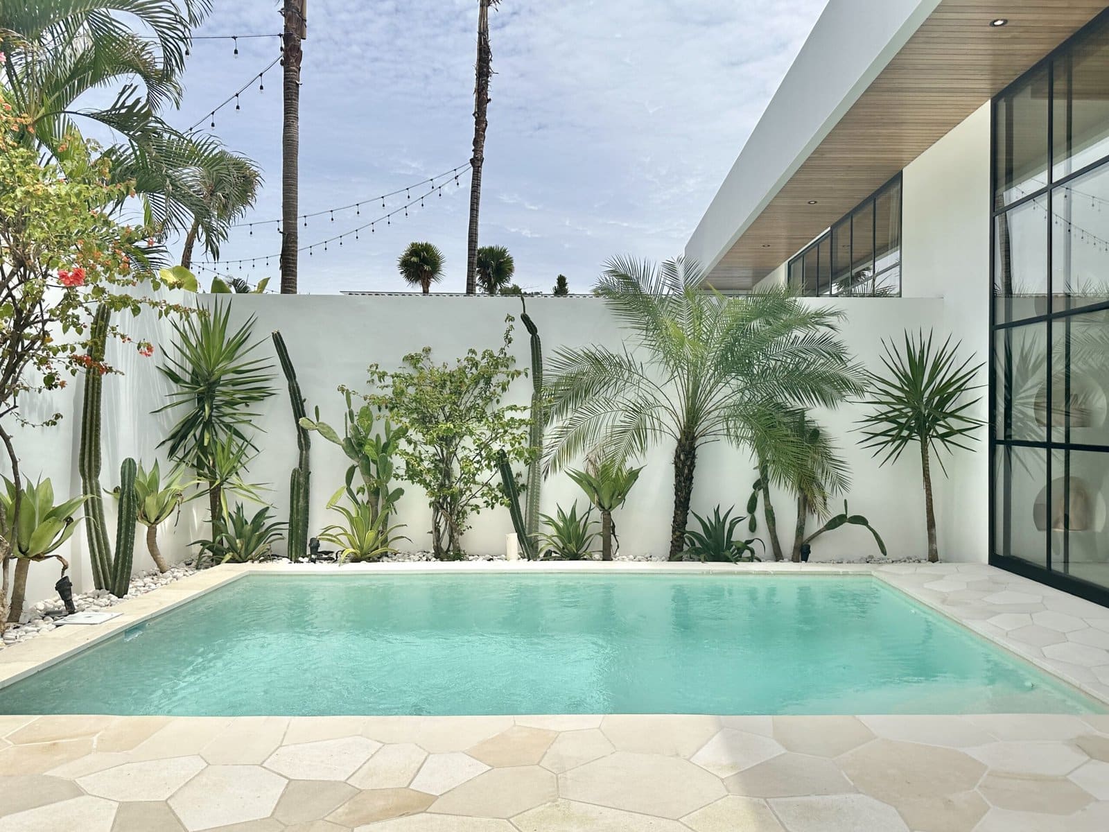 High-end tropical-modern vacation rental in Uluwatu, Bali, featuring a sleek pool and lush greenery.