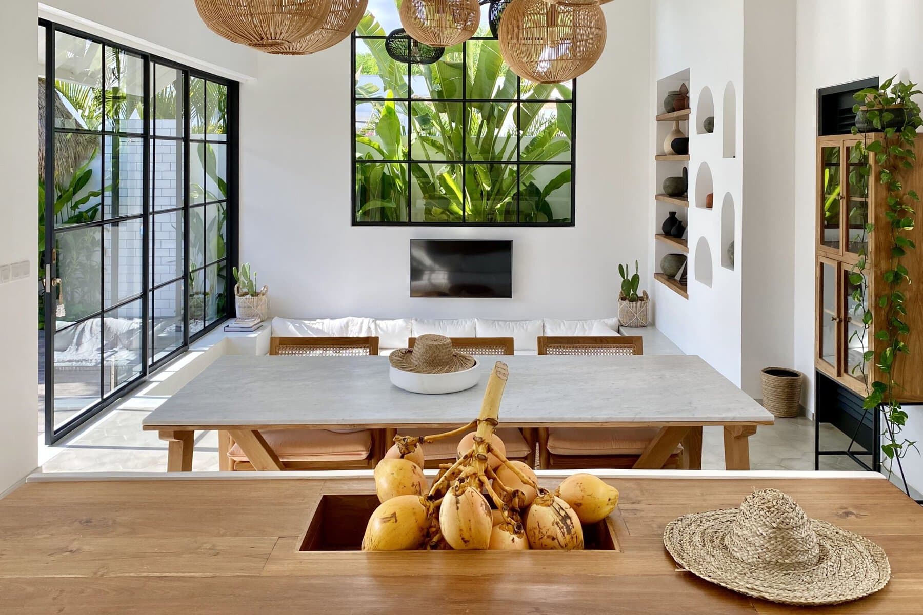 Bright modern living space with tropical decor and large windows.