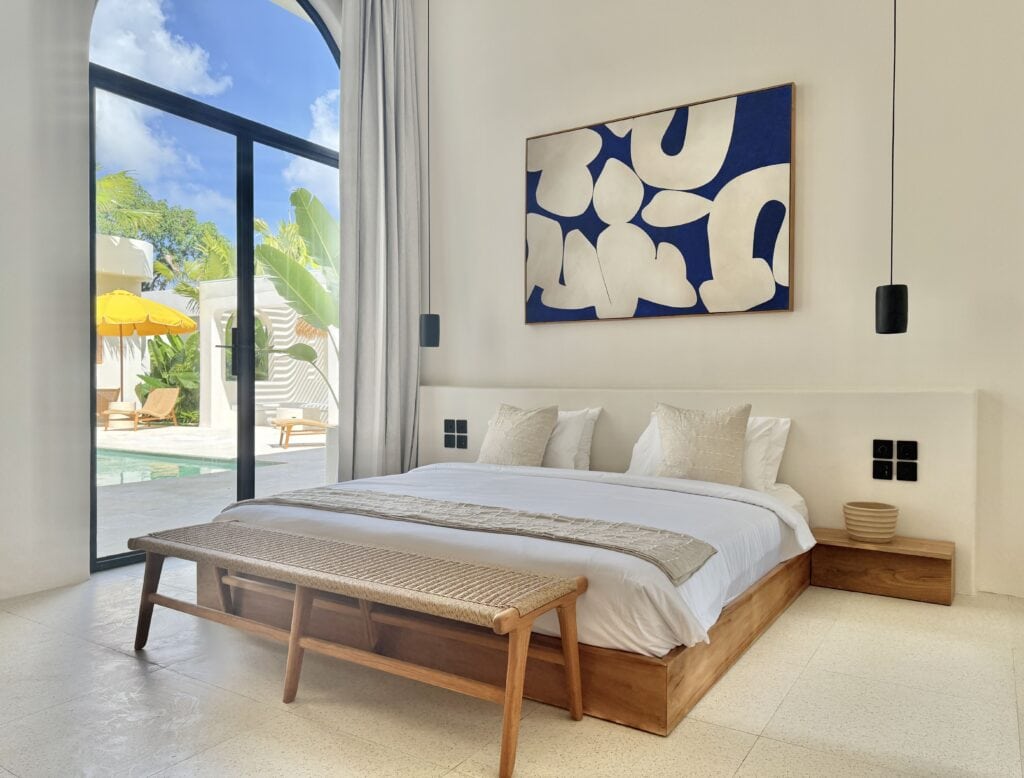 Luxurious bedroom with poolside view, neutral tones, and modern design elements.