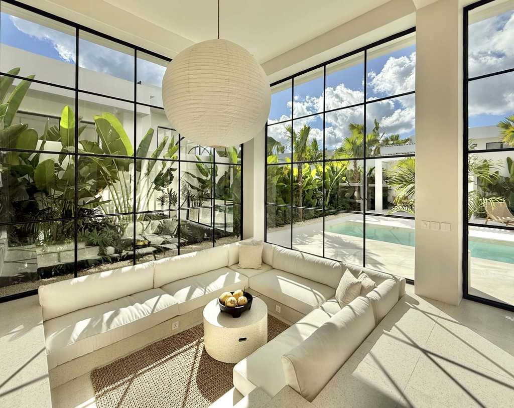 Bright tropical-modern living room with large windows and garden view.