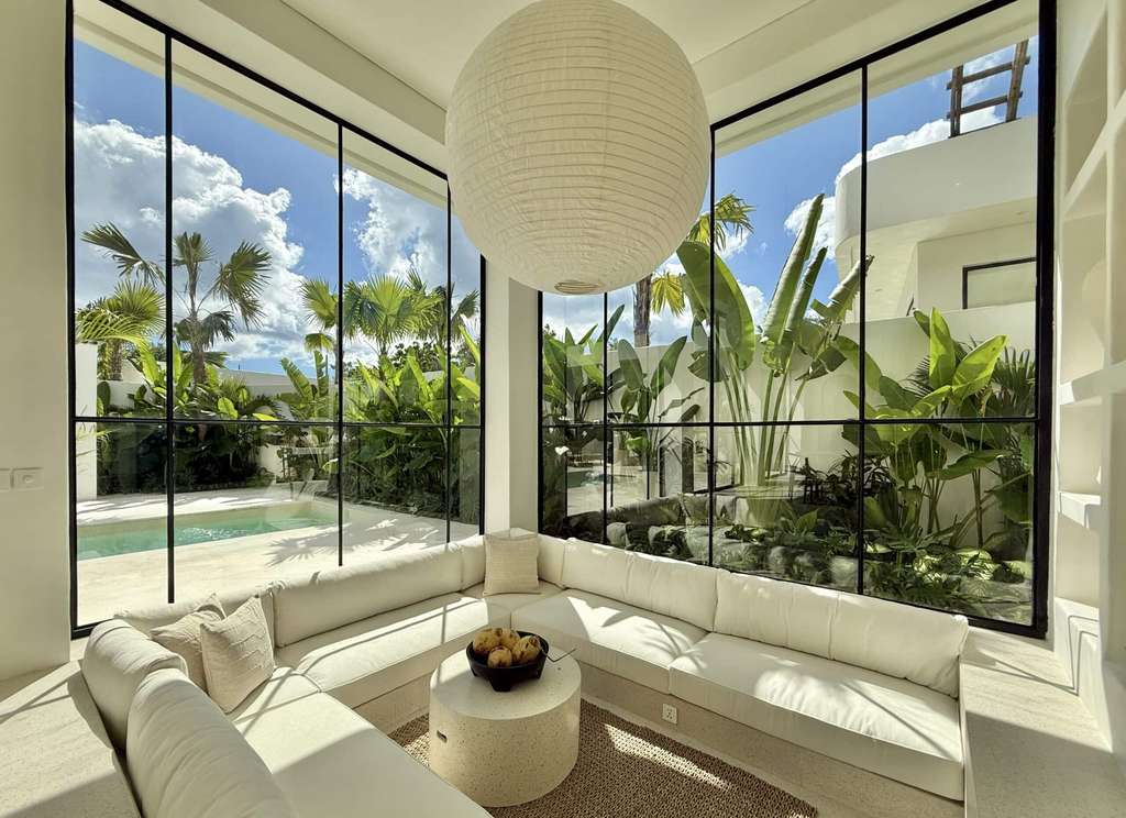 Spacious living room with floor-to-ceiling windows overlooking lush tropical gardens in Uluwatu.