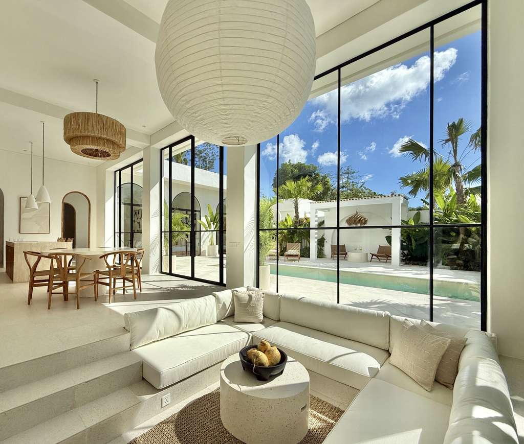 Bright living room with floor-to-ceiling windows, tropical views, and modern minimalist decor.