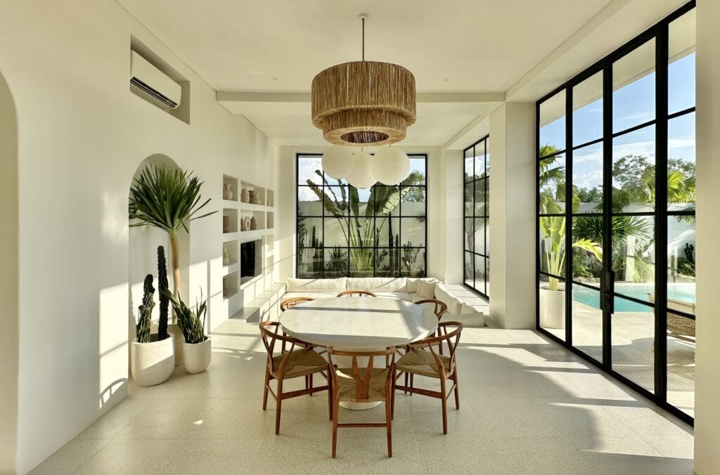 Spacious living space in Uluwatu with large windows, lush outdoor view, and stylish furnishings.