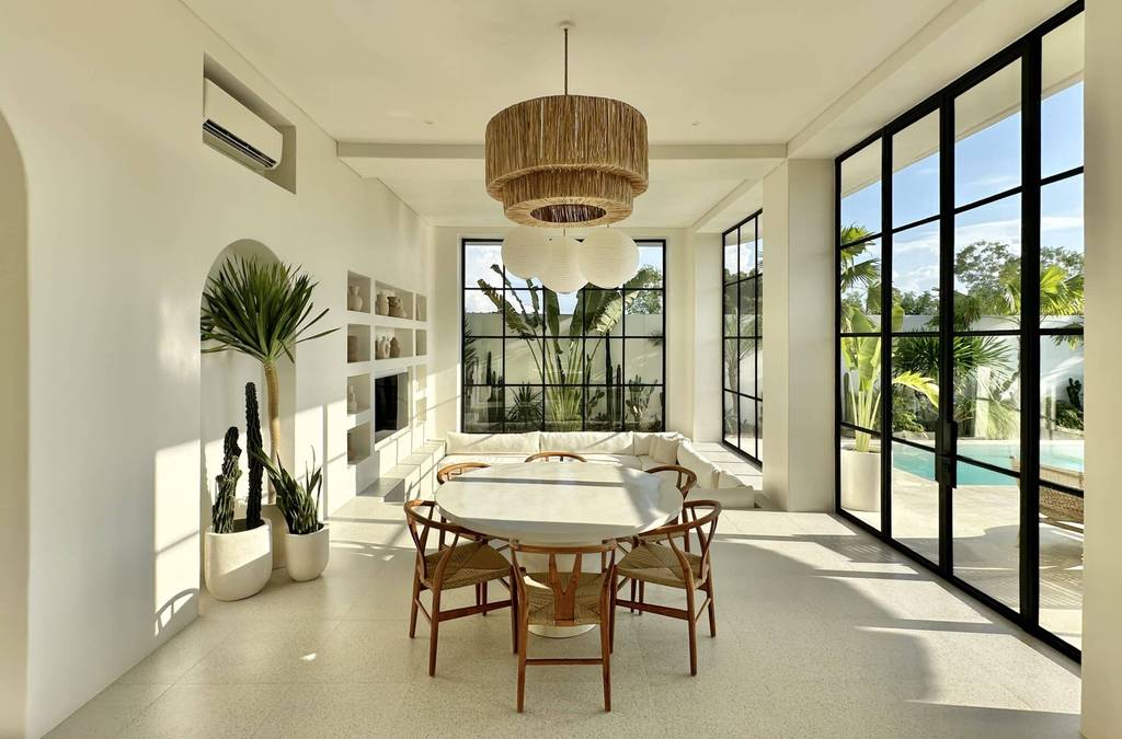 Spacious living space in Uluwatu with large windows, lush outdoor view, and stylish furnishings.
