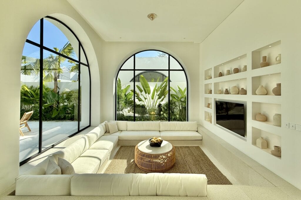 Bright airy living room with large arched windows and tropical views.