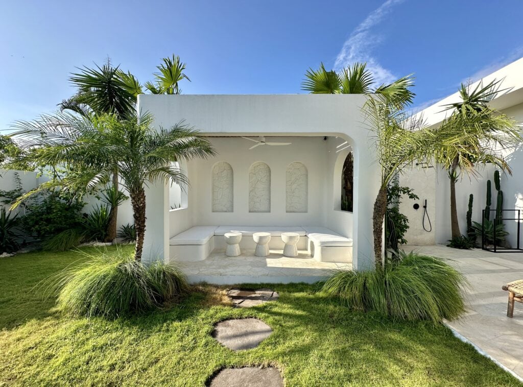 Beautiful white minimalist outdoor lounge with lush palm trees in Bali.