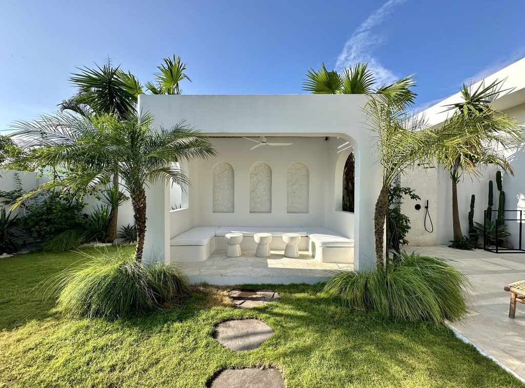 Beautiful white minimalist outdoor lounge with lush palm trees in Bali.