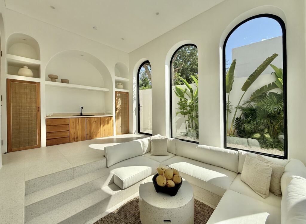 Spacious minimalist living room with large windows showcasing lush tropical greenery in Uluwatu’s luxury villa.
