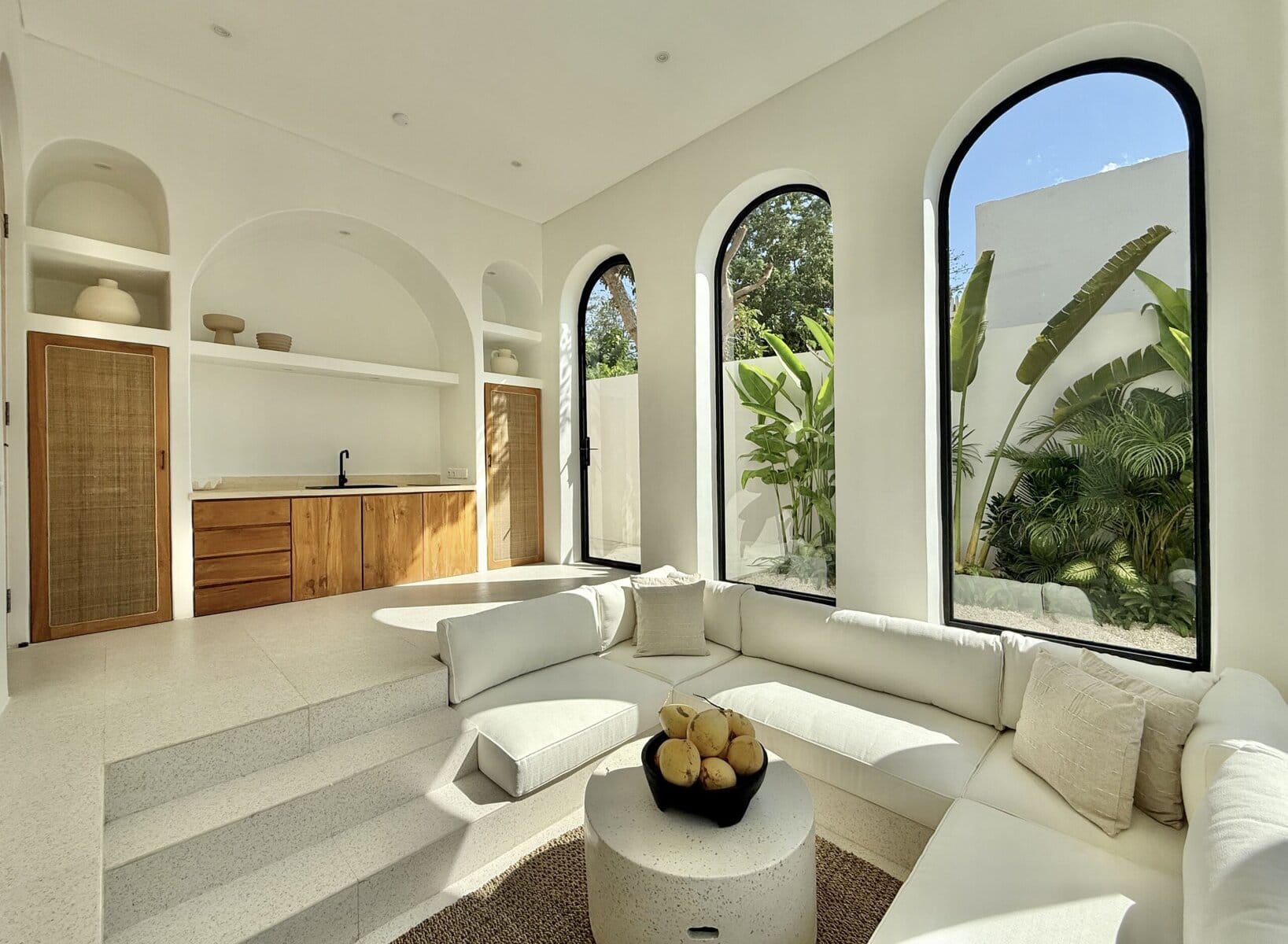 Spacious minimalist living room with large windows showcasing lush tropical greenery in Uluwatu’s luxury villa.