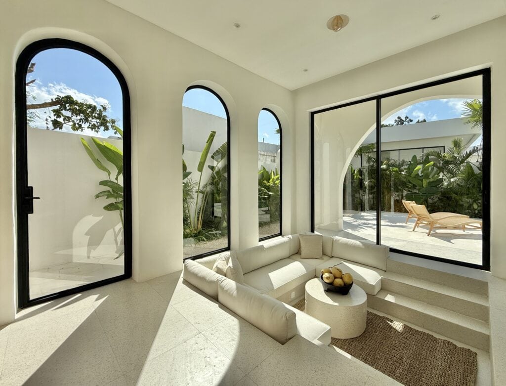 Bright modern tropical interior with large windows and outdoor patio.