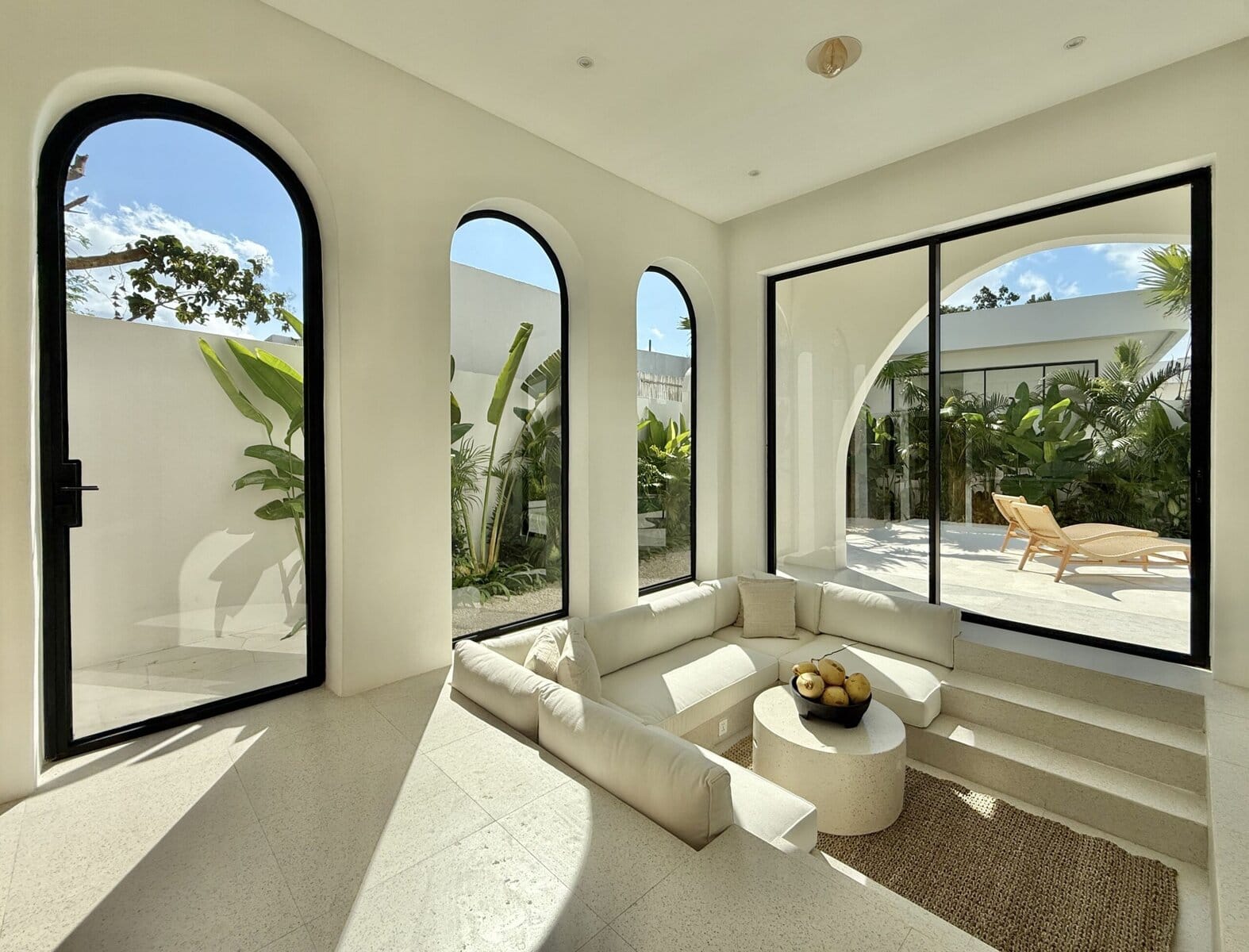 Bright modern tropical interior with large windows and outdoor patio.