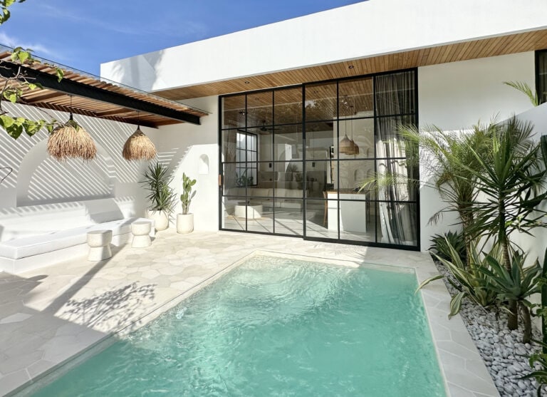Bright, stylish villa featuring a pool, glass doors, and lush decor, perfect for a Bali getaway.