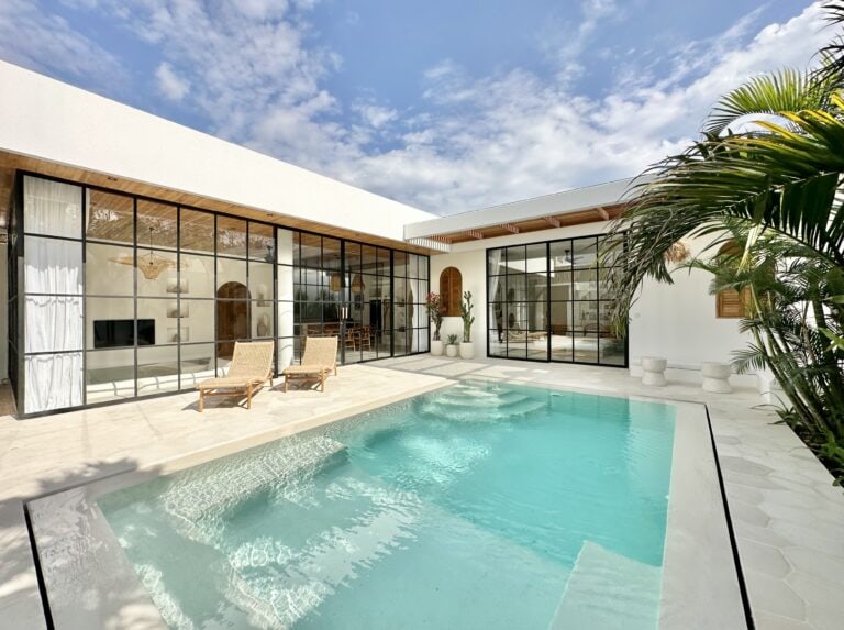 Stylish modern villa with pool, featuring floor-to-ceiling glass doors and tropical decor.