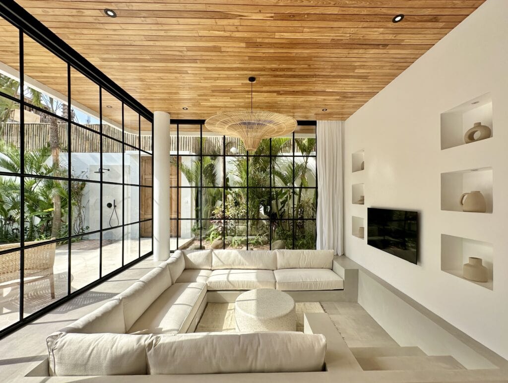 Bright modern living room with large glass windows and tropical views.