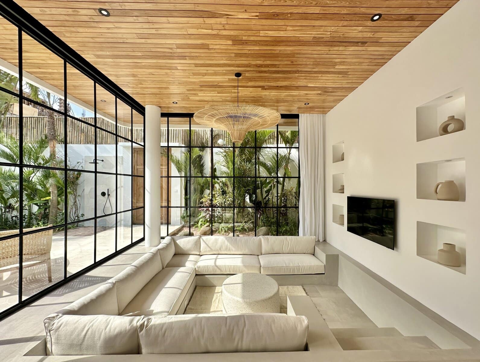 Bright modern living room with large glass windows and tropical views.