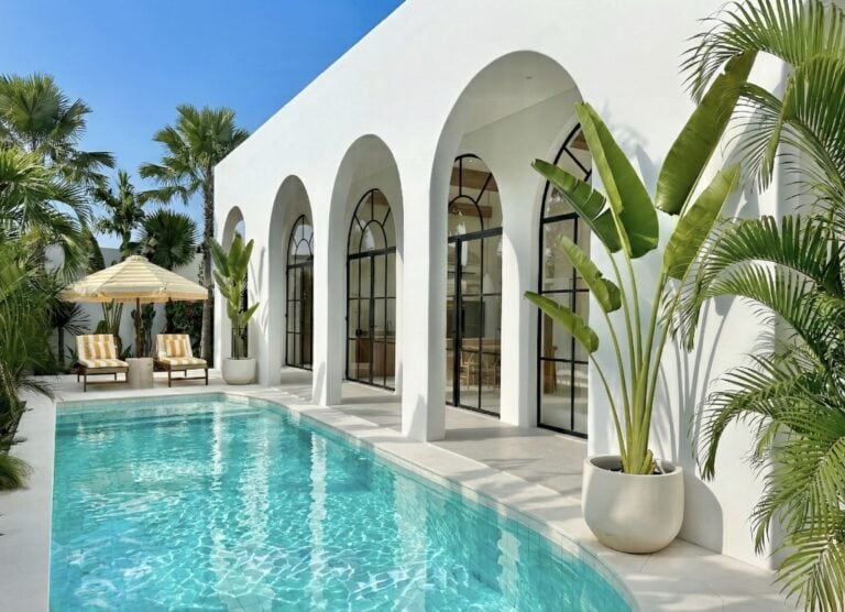 Sliding glass doors connecting a modern villa bedroom directly to the pool terrace.
