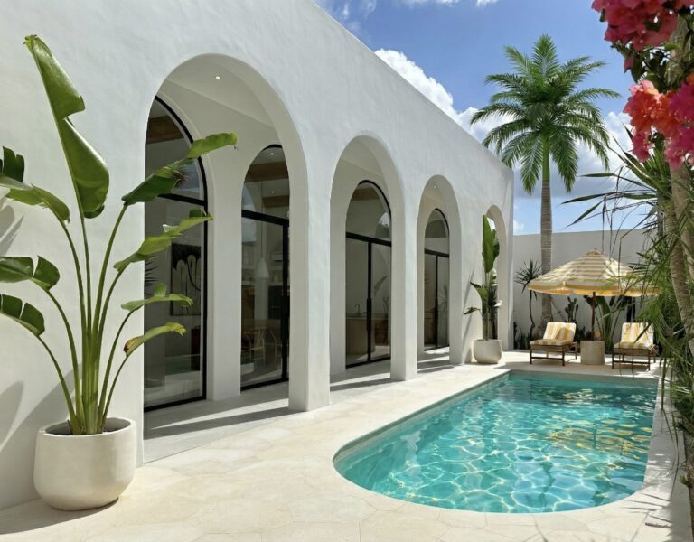 Minimalist stone pool deck with rattan sun loungers and tropical landscaping.