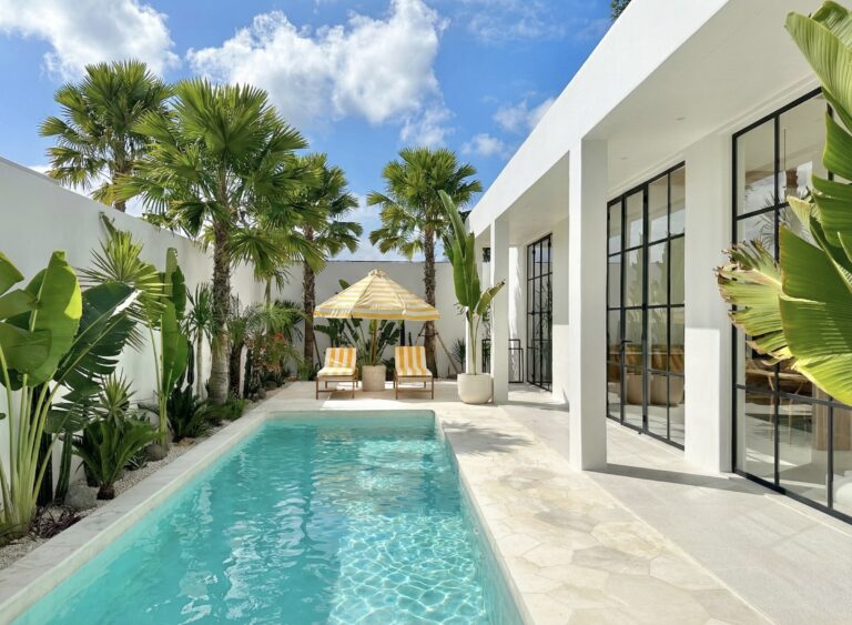 Crystal clear turquoise swimming pool reflecting sunlight in a tropical villa garden.