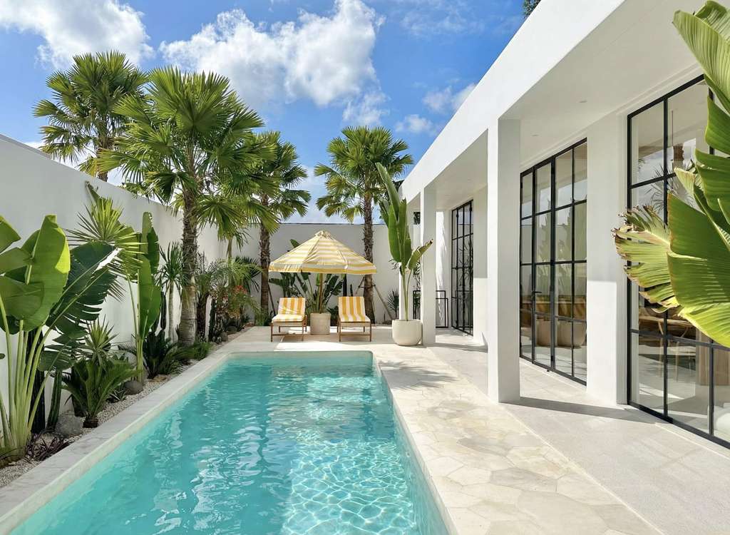 Crystal clear turquoise swimming pool reflecting sunlight in a tropical villa garden.