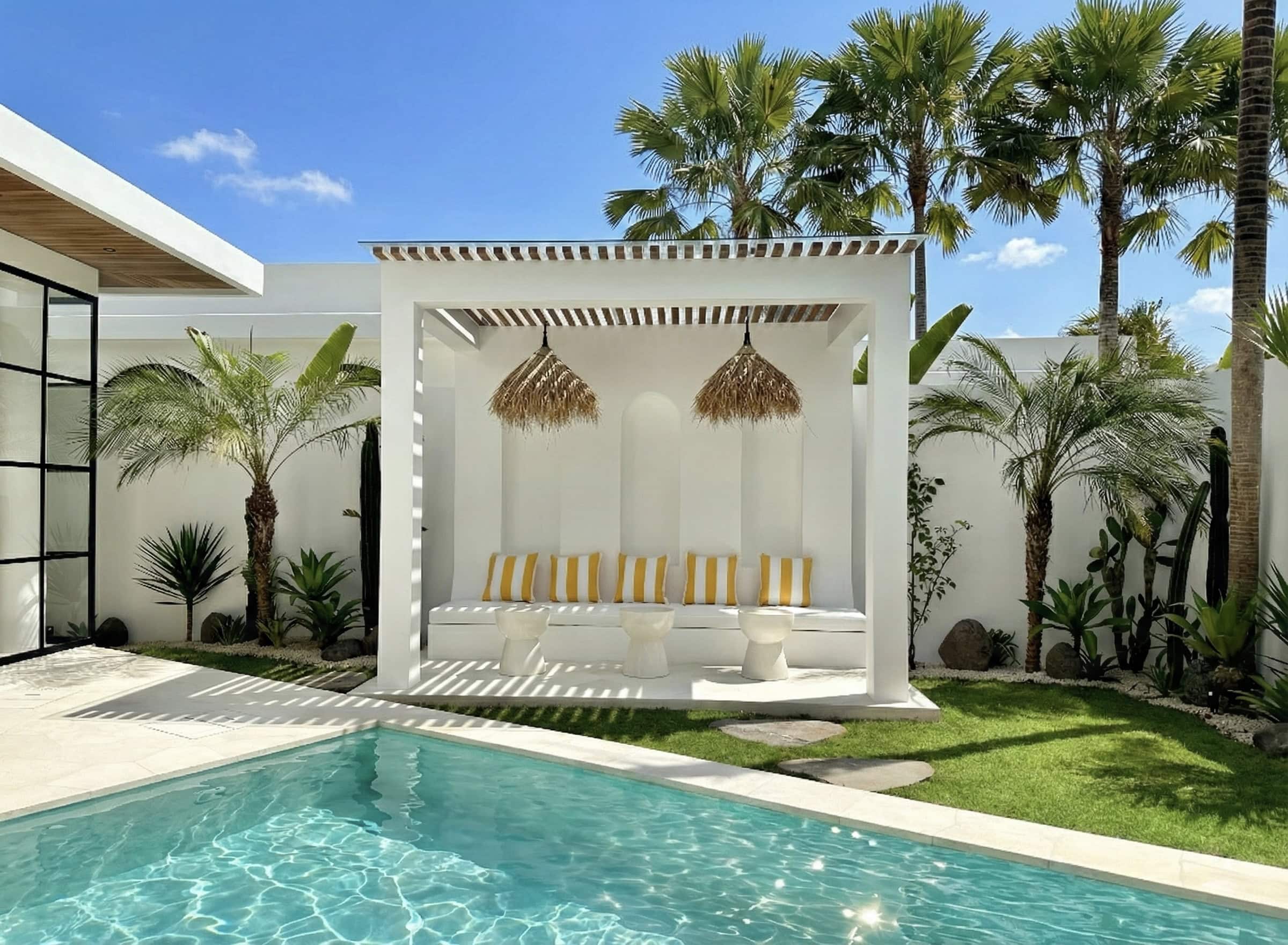 The Young Villas: Elegant tropical-modern poolside lounge with lush greenery in Seseh, Bali.