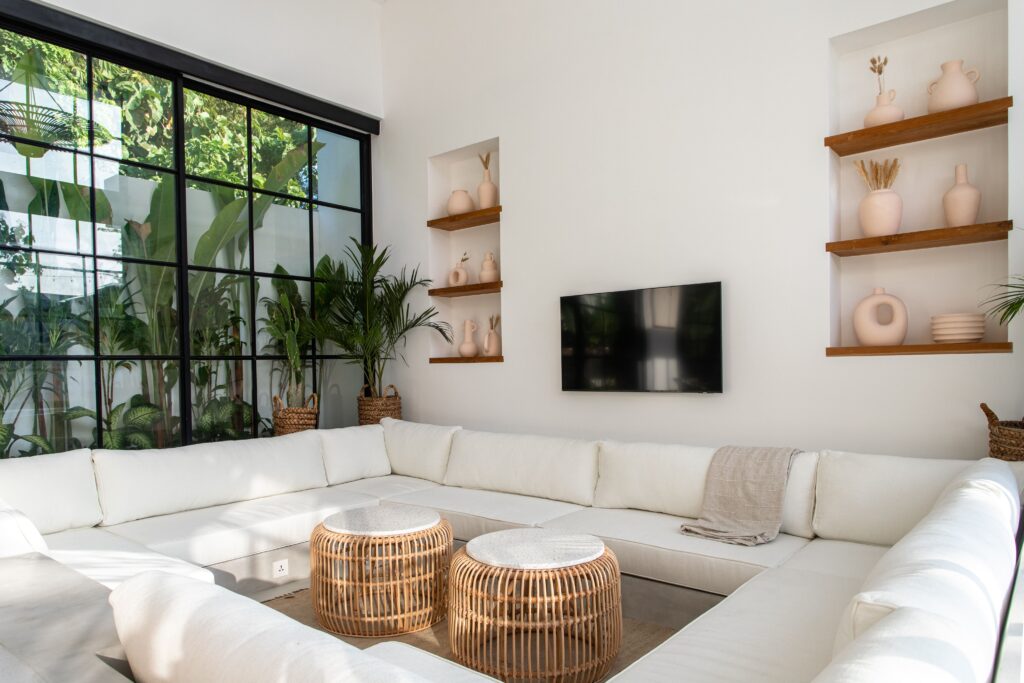 Bright minimalist living room with white sofa, wicker tables, and tropical plants in Bali.
