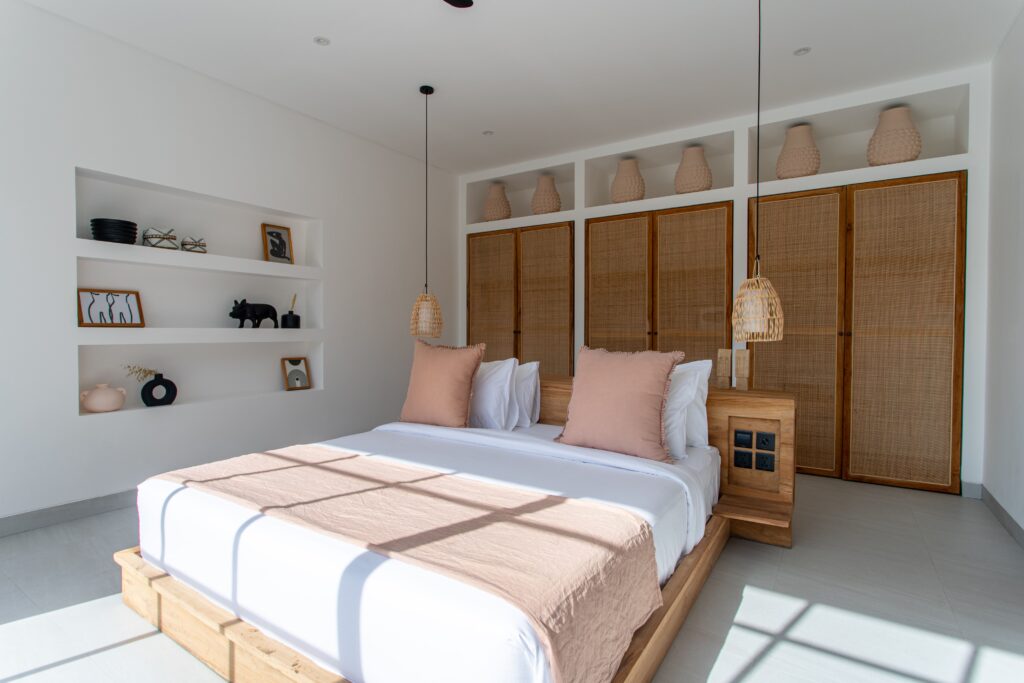 Minimalist bedroom with natural wood accents, bright sunlight and modern decor. Perfect for a luxurious stay.