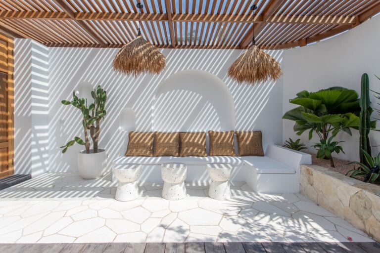 Stylish outdoor lounge with shaded seating, tropical plants, and minimalist decor in Uluwatu, Bali.