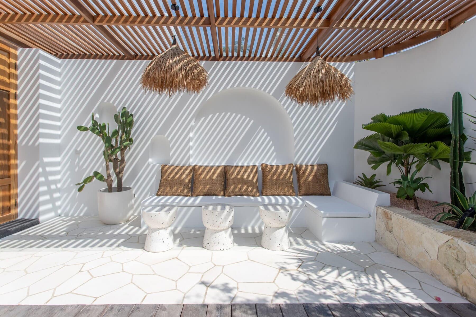 Stylish outdoor lounge with shaded seating, tropical plants, and minimalist decor in Uluwatu, Bali.