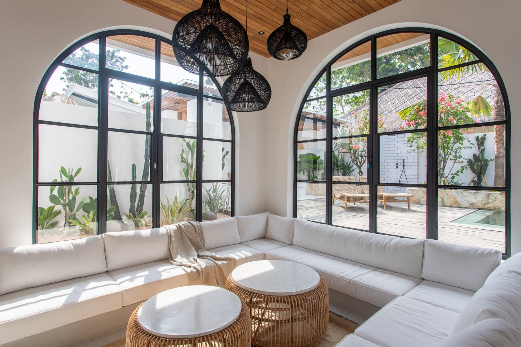 Bright living room with large arched windows and tropical decor.
