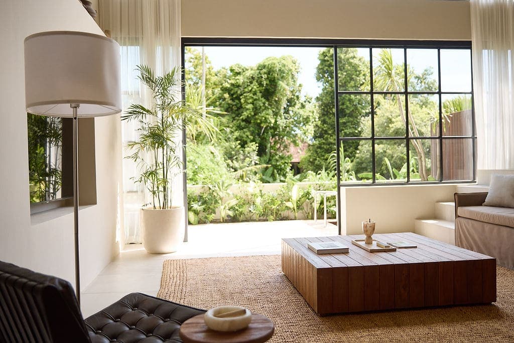 Elegant minimalist living room with lush garden view and high-end furnishings.