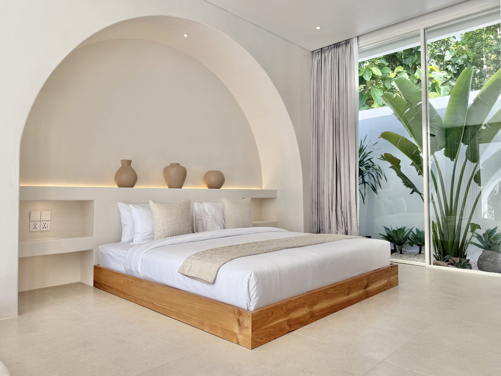 Elegant minimalist bedroom with natural light and lush greenery view.