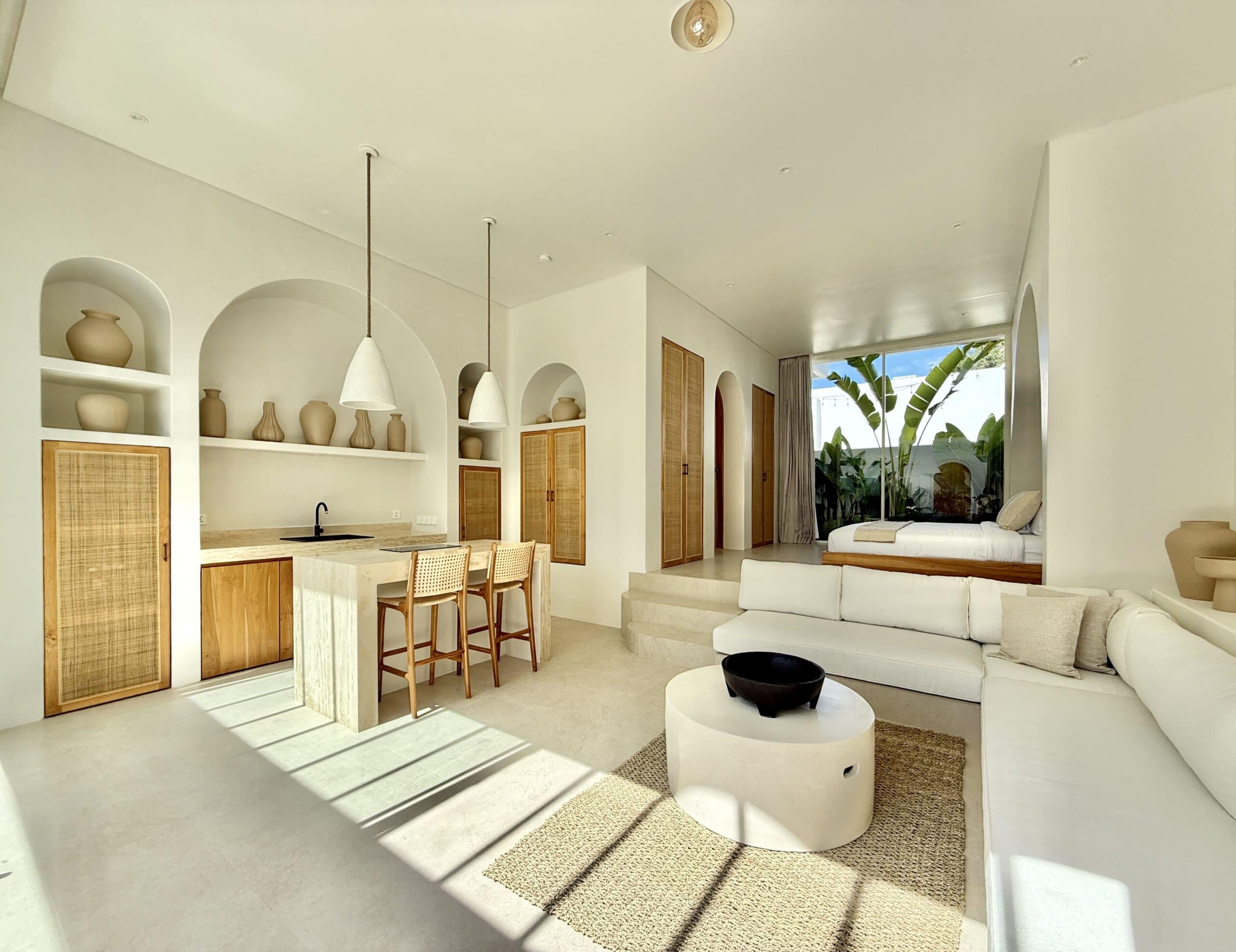 Bright, minimalist living space with neutral tones, natural light, and tropical decor.